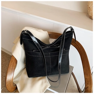 Détail du sac cabas en daim noir avec surpiqûres blanches et nœud décoratif élégant