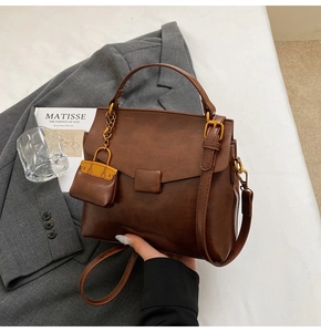 Detail of coffee brown retro small square bag with glossy texture and mini purse charm