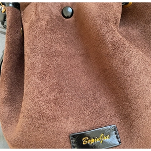 Gros plan sur la texture en daim marron avec étiquette en cuir noir et bouton métallique