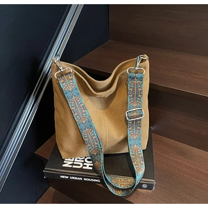 Detail of khaki canvas bucket bag with vintage ethnic jacquard strap and silver hooks
