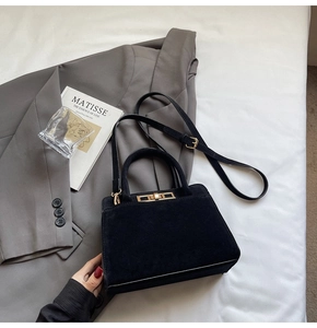 Detailed view of black suede texture handbag with golden clasp and hardware
