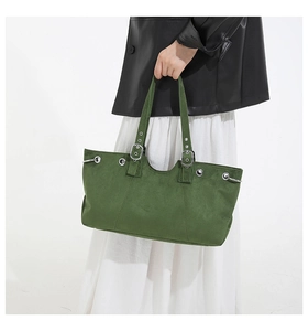 Detail of moss green suede tote bag featuring silver metal eyelets and adjustable handle
