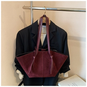Detail of burgundy suede tote bag featuring elegant knotted shoulder straps on a blazer