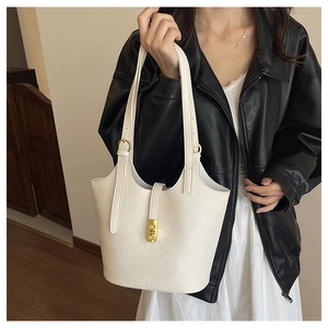 Detailed close-up of white leather bucket tote bag featuring adjustable strap and gold buckle