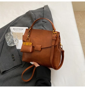 Detail view of brown vintage crossbody bag with matte finish and mini pouch charm