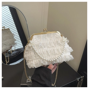 Détail du sac élégant en dentelle crème avec poignée en perles et bandoulière
