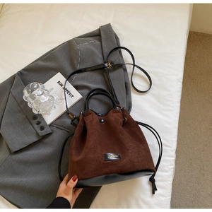 Vue détaillée du sac seau en daim marron avec garniture en cuir noir et cordon de serrage