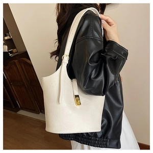 Detailed view of white leather tote bag with gold twist lock and adjustable shoulder strap