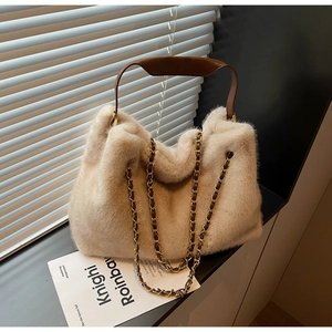 Detailed view of beige plush bucket bag with brown leather handle and gold chain strap