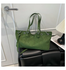 Detail of green faux suede tote bag featuring silver eyelets and adjustable buckle strap