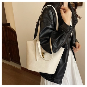 Detail of cream leather tote bag featuring a polished gold buckle and fine grain texture