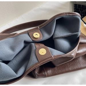 Detail view of brown soft leather tote bag showing grey suede lining and magnetic closures