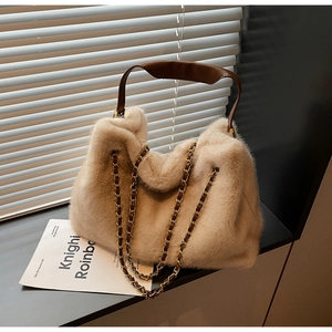 Detail of beige plush tote bag with brown leather handles and decorative chain strap