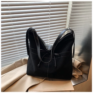 Détail d'un sac cabas noir avec coutures contrastées blanches et texture mate et élégante