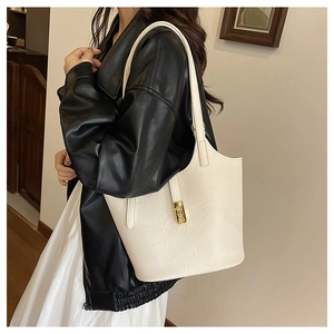 Close-up of cream white tote bag featuring smooth faux leather and gold metal buckle detail