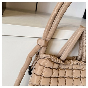 Détail d'un sac cabas matelassé doré avec vue sur la texture et les bretelles rembourrées