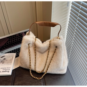 Detail of plush beige faux fur tote bag with brown leather handle and gold chain