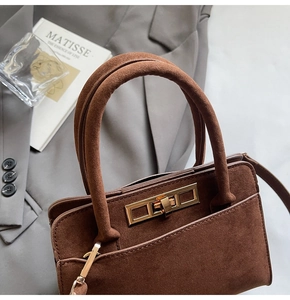 Detail of dark brown matte handbag with a luxury golden metal twist lock and suede texture