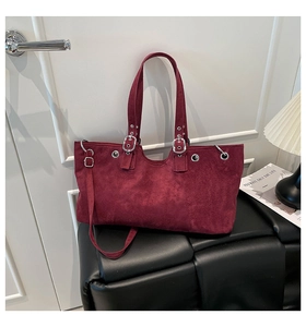 Detail of burgundy suede tote bag featuring silver grommets and adjustable buckle handles