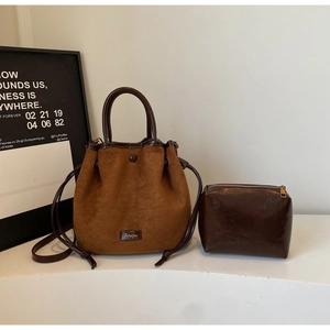 Vue détaillée du sac seau en daim marron avec anses en cuir et petite pochette assortie