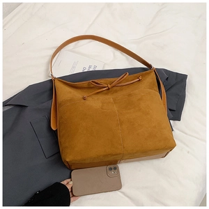 Gros plan sur la texture mate et les coutures blanches du grand sac fourre-tout marron