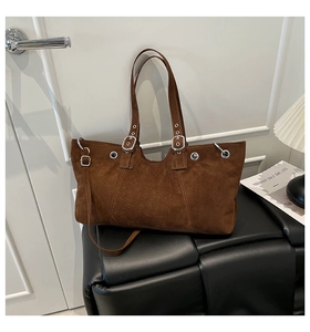 Close-up of vintage brown suede tote bag with metallic eyelets on wide straps