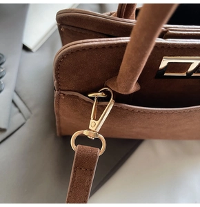 Close-up of golden metal lobster clasp and premium suede texture on brown tote bag
