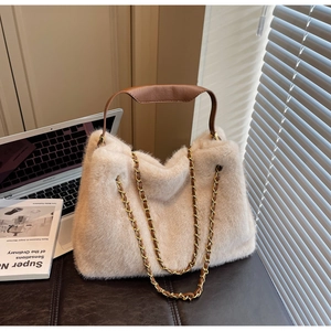 Detailed view of plush off-white faux fur tote bag with brown leather handle and gold chain