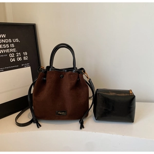 Vue détaillée du sac seau en suédine marron et de la pochette en cuir noir sur fond neutre
