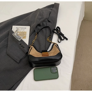 Minimalist black and tan underarm bag shown with phone for size reference and metal chain