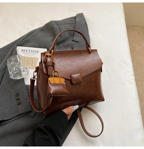 Top view of a brown vintage leather handbag with a flap closure and mini charm detail