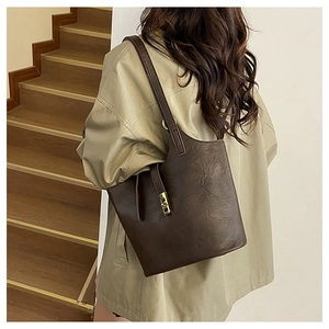 Detail of vintage dark brown faux leather tote bag with gold metal buckle on a model