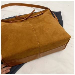 Détail d'un sac cabas en daim marron et cuir avec un nœud décoratif élégant