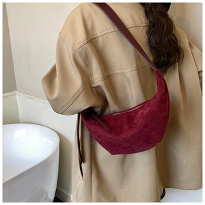 Detailed back view of a burgundy suede moon bag with silver zipper on a beige trench coat