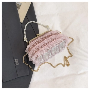 Gros plan du sac en dentelle rose avec poignée en perles et détails de nœuds blancs