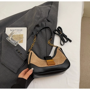 Detail of suede crossbody bag with gold buckle on grey blazer background
