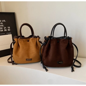 Détail des sacs seaux en daim avec fermeture à cordon et bordures en cuir contrastées
