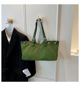 Close-up of bright green canvas tote bag with silver eyelets and adjustable strap buckles