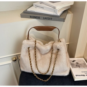 Detail of soft cream faux fur tote bag with brown leather handles and gold chain accents