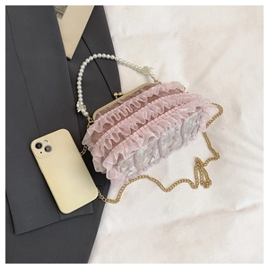 Vue détaillée du sac en dentelle rose avec poignée en perles et fermoir en métal doré