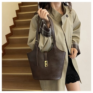 Detail of dark brown tote bag showing gold buckle and retro oily leather texture