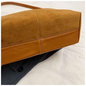Détails de sac en daim marron avec surpiqûres blanches contrastées et empiècements cuir