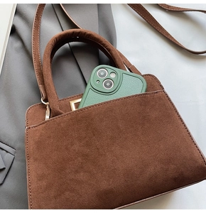 Detail of a brown suede tote bag showing front pocket and interior phone storage capacity