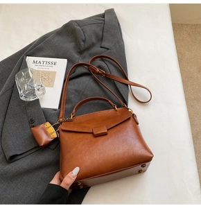 Detail of vintage brown leather handbag with matching mini pouch and gold metal feet