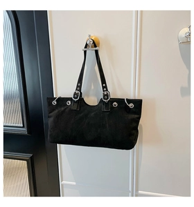 Detail of vintage black suede tote bag with silver metal buckles and punk style hardware