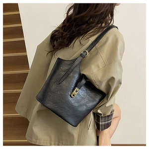 Detail of classic black leather tote bag with gold swivel clasp on a shoulder strap