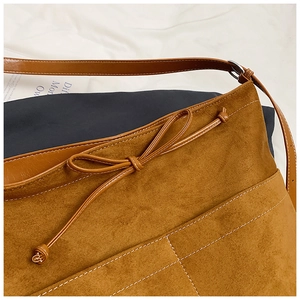 Détail macro du sac cabas marron mat avec nœud décoratif et coutures contrastées élégantes