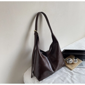 Close-up of soft dark brown PU leather hobo bag with vintage texture and golden buckle