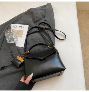 Close-up of black leather handbag with gold hardware and small zipper coin purse detail