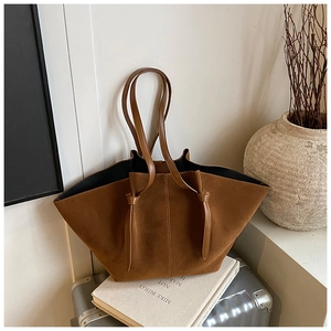 Detail of a brown suede tote bag with knotted strap and minimalist retro design
